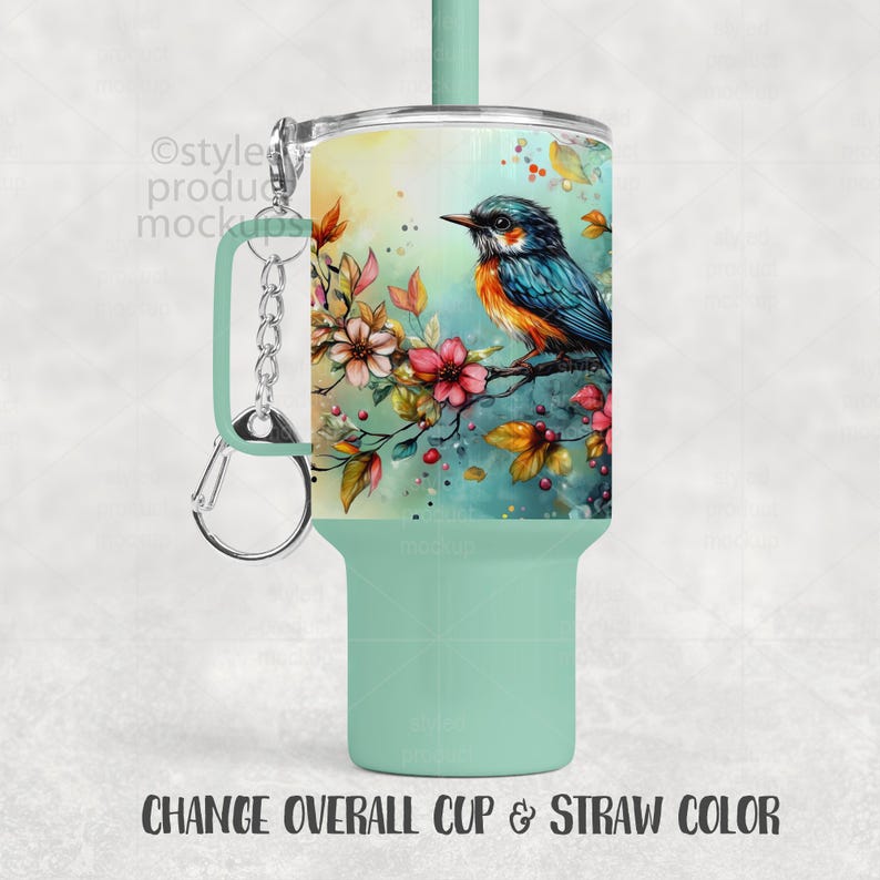 May include: A mint green tumbler with a bird and floral design. The tumbler features a colorful watercolor illustration of a blue and orange bird perched on a branch with pink flowers. The text at the bottom reads "CHANGE OVERALL CUP & STRAW COLOR."