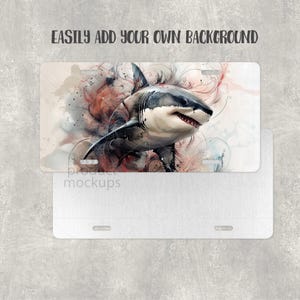 May include: Rectangular license plate with a striking image of a great white shark. The shark is painted in shades of grey and white, with red accents, against a backdrop of abstract swirls. The text "EASILY ADD YOUR OWN BACKGROUND" is displayed at the top.