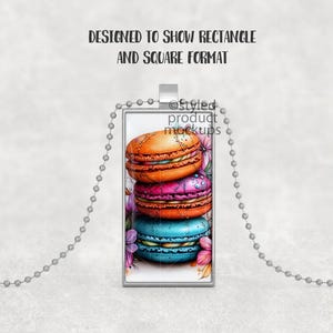 May include: A silver chain necklace with a rectangular pendant featuring a stack of colorful macarons. The macarons are decorated with white frosting and flowers.