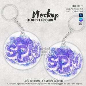 May include: Two round MDF keychain mockups with a silver chain and ring. The keychains have a white background with a purple and blue watercolour design and the letters "SPM". The text "Mockup" and "Round MDF Keychain" are at the top.