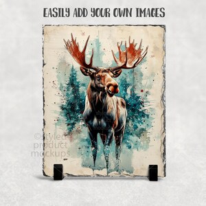 Puede incluir: Una pizarra decorativa con una ilustraci&oacute;n en acuarela de un alce con grandes astas. El alce se encuentra sobre un fondo de &aacute;rboles de color verde azulado y un fondo azul claro. El texto "EASILY ADD YOUR OWN IMAGES" est&aacute; en la parte superior.
