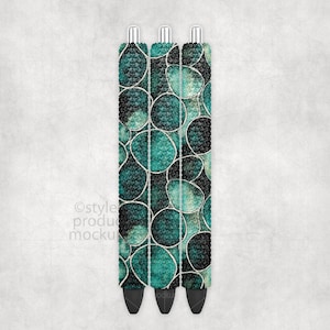 May include: Three pens with a teal and black abstract pattern. The pens have silver tips and black ink tips. The pattern is made of circles and lines. The pens are on a white background.