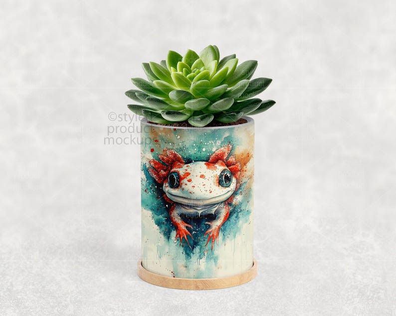 May include: A cylindrical planter pot featuring a watercolor axolotl design in shades of red, white, and blue. The pot holds a green succulent plant. The pot sits on a small, round, light brown base.