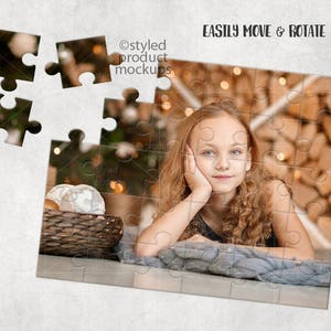 May include: A young girl with long brown hair is lying on a blue blanket. She is looking at the camera with a smile. The background is a blurred image of a wooden wall with lights. The image is a jigsaw puzzle with some pieces missing.