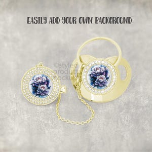 May include: Gold-colored baby pacifier and clip set. The pacifier and clip feature a floral design with purple and blue flowers, surrounded by clear rhinestones. The text "EASILY ADD YOUR OWN BACKGROUND" is at the top.