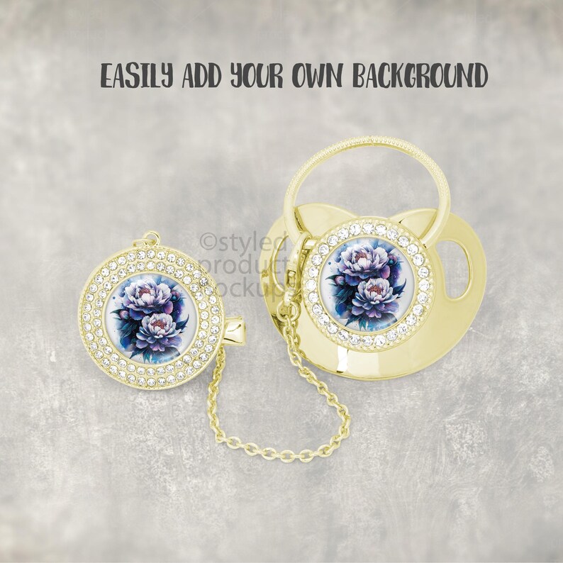 May include: Gold-colored baby pacifier and clip set. The pacifier and clip feature a floral design with purple and blue flowers, surrounded by clear rhinestones. The text "EASILY ADD YOUR OWN BACKGROUND" is at the top.