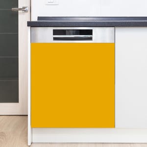 Puede incluir: Un lavavajillas que presenta un panel magn&eacute;tico de color amarillo mostaza vibrante y s&oacute;lido. El electrodom&eacute;stico tiene un panel de control de acero inoxidable en la parte superior con un asa horizontal, integrado en una cocina blanca.