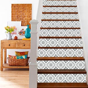 May include: Wooden staircase with decorative gray and white patterned stair risers. The risers feature a repeating floral design. A wooden console table with decor is visible to the left of the stairs.