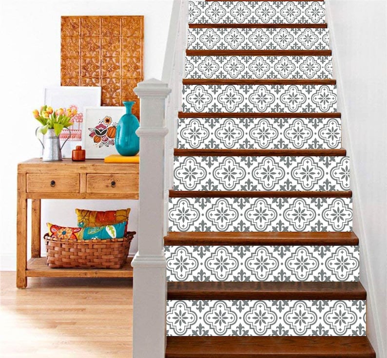 May include: Wooden staircase with decorative gray and white patterned stair risers. The risers feature a repeating floral design. A wooden console table with decor is visible to the left of the stairs.