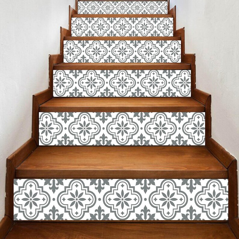May include: Wooden staircase with decorative gray and white patterned stair risers. The pattern features a floral and geometric design. The steps are made of a warm-toned wood, creating a contrast with the cool-toned risers. The design adds a touch of elegance.