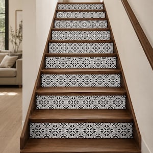 May include: A staircase featuring dark wood treads and risers decorated with black and white patterned adhesive decals. The repeating design on each riser consists of intricate floral and geometric motifs, creating a high-contrast visual effect.