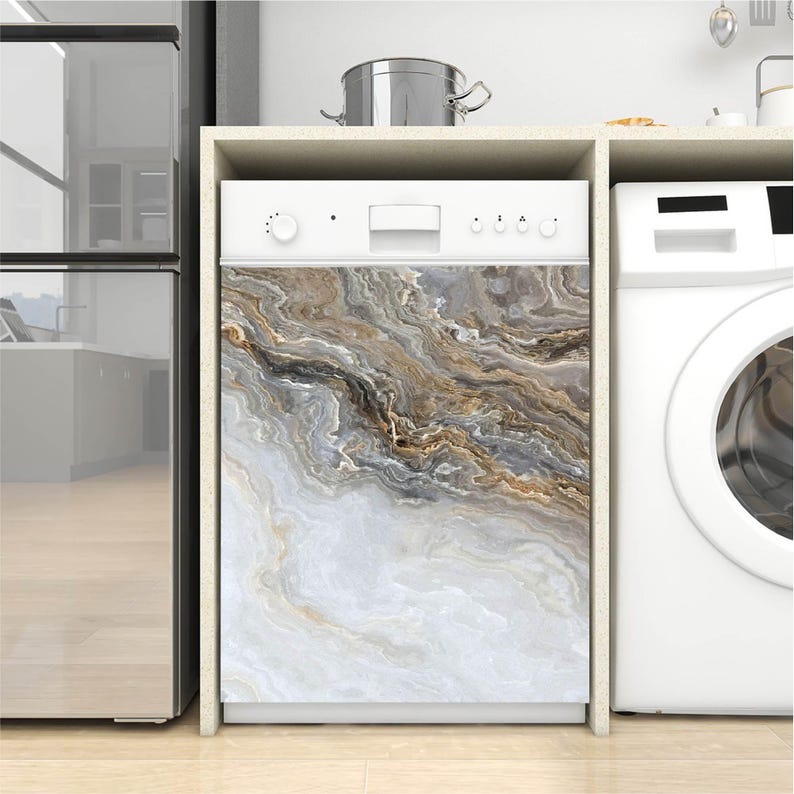 May include: A white dishwasher with a decorative front panel featuring a marble-like design in shades of brown, gray, and white. The kitchen appliance is positioned between a stainless steel refrigerator and a white washing machine.