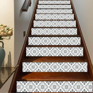 May include: Wooden staircase with decorative stair treads featuring a gray and white floral pattern. The treads are applied to the front of each step, creating a stylish and patterned design element in the home.