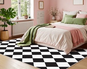 May include: A rectangular area rug featuring a repeating black and white diamond pattern. The rug is positioned on a light-colored wooden floor in a room with pink walls, a bed with green and pink bedding, and a large green potted plant nearby.