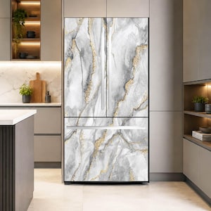 May include: A French door refrigerator featuring a wrap-around design with a grey and white marble pattern accented by shimmering gold veins. The appliance has two vertical upper doors with long silver handles and a single horizontal bottom freezer drawer.