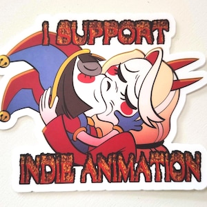 Peut inclure: Autocollant avec une illustration de deux personnages de dessins animés s'embrassant. L'un porte un chapeau de bouffon rouge et bleu, l'autre a des cheveux blonds et des cornes rouges. Le texte "I SUPPORT INDIE ANIMATION" est affiché.