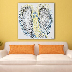 May include: Abstract painting of an angel with blue, yellow and black paint on a white canvas. The painting is signed "Anebhi" in the bottom right corner.