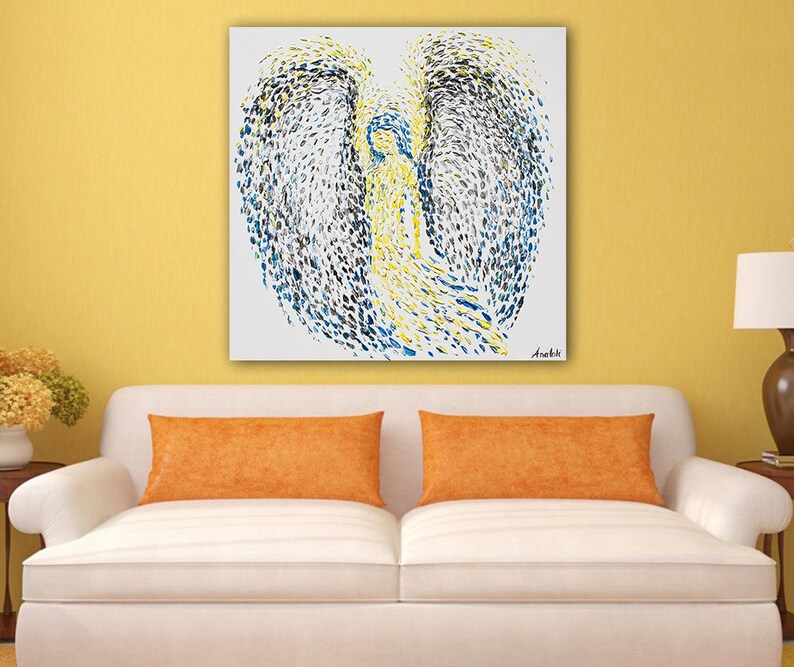 May include: Abstract painting of an angel with blue, yellow and black paint on a white canvas. The painting is signed "Anebhi" in the bottom right corner.