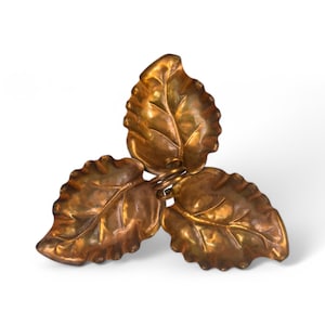 May include: A three-leaf design, copper trinket dish. The leaves are embossed with a detailed vein pattern and have a slightly aged, antique finish.