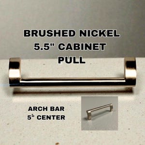 Könnte beinhalten: Schrankgriff aus gebürstetem Nickel mit einem Bogendesign. Der Hauptgriff ist 14 cm lang, mit einem Lochabstand von 12,7 cm. Das Bild enthält auch eine kleinere Version des Griffs.