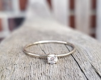 Op de afbeelding: Een eenvoudige zilveren ring met een enkele, kleine, ronde, heldere edelsteen.