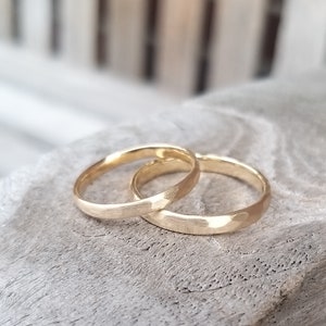 Puede incluir: Dos alianzas de oro con acabado martillado. Las alianzas est&aacute;n apiladas una encima de la otra.