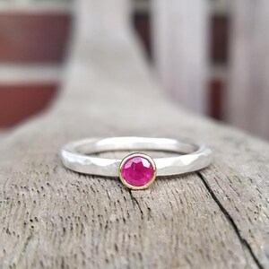 Peut inclure: Une bague en argent avec une texture martelée et une seule pierre précieuse en rubis sertie dans une bélière en or.