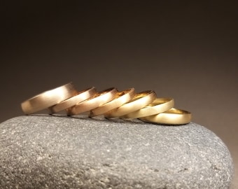 Pode incluir: Um gancho de parede branco com uma placa central oval e detalhes ornamentais simétricos. O acabamento é desgastado, revelando metal castanho escuro sob a tinta branca, criando uma aparência texturizada e envelhecida.