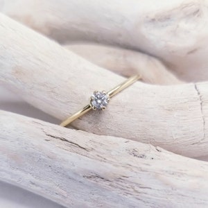 Op de afbeelding: Een delicate gouden ring met een enkele, kleine, ronde diamant in het midden.