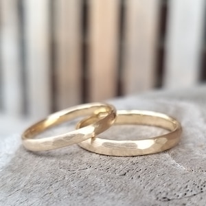 Puede incluir: Dos alianzas de oro con acabado martillado. Las alianzas est&aacute;n apiladas una encima de la otra.