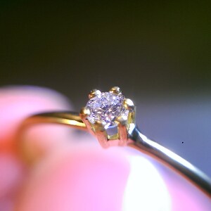Op de afbeelding: Een eenvoudige gouden ring met een kleine, heldere diamant in een vier-klauw-zetting.