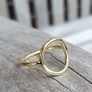 Könnte beinhalten: Ein goldfarbener Ring mit einem einfachen Kreisdesign. Der Ring ist aus Metall und hat eine glatte Oberfläche.