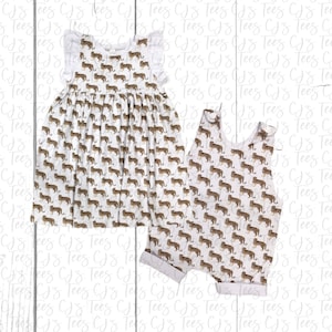 May include: A white sleeveless romper and a white dress with a brown cheetah print pattern. Both garments have ruffles on the shoulders.