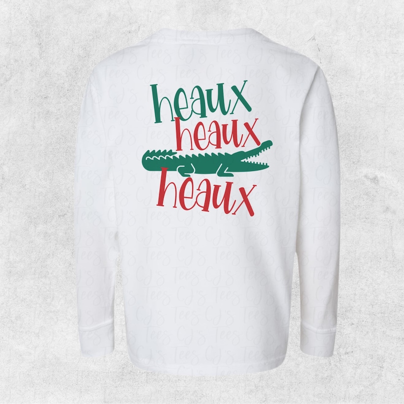 May include: White long-sleeve t-shirt with a green alligator and the text "Heaux Heaux Heaux" in red.