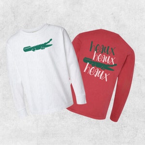 May include: Two long-sleeved shirts, one white with a green alligator graphic and the other red with the text "heaux heaux heaux" in pink.