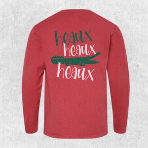 May include: Red long-sleeve t-shirt with a green alligator and the text "Heaux Heaux Heaux" printed on the back.