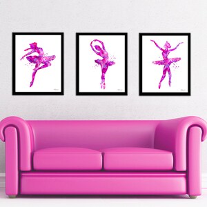 Puede incluir: Tres acuarelas de bailarinas en tonos rosas y morados. Cada bailarina est&aacute; en una pose diferente, una con los brazos por encima de la cabeza, otra con los brazos a los lados y la &uacute;ltima con los brazos extendidos. Las pinturas est&aacute;n enmarcadas en marcos negros y est&aacute;n colgadas en una pared blanca.