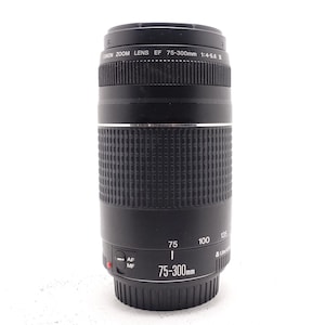 Puede incluir: Un objetivo zoom Canon negro, modelo EF 75-300mm 1:4-5.6 III, con un agarre acanalado y ajustes de enfoque. El objetivo tiene marcas para 75, 100 y 135 mm. Diseñado para cámaras Canon.