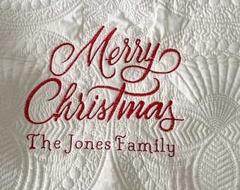 May include: White quilted blanket with red embroidered text that reads "Merry Christmas The Jones Family".