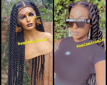 May include: A black braided wig on a mannequin head and a person with a similar hairstyle. The wig is long and features thick, twisted braids. The person is wearing sunglasses and a black top. The text "@eminadohair" is visible.