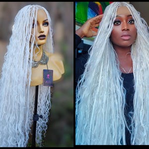 May include: A long, white, curly synthetic hair wig. The wig is styled in long, loose braids. The wig is on a mannequin head and a person is wearing the same wig.