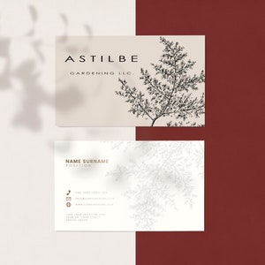 May include: A white business card with black text that reads "ASTILBE GARDENING LLC." and a black and white illustration of a fern. The card has a white background with a light gray shadow.