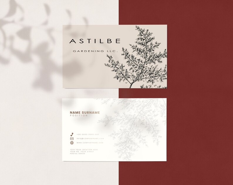 May include: A white business card with black text that reads "ASTILBE GARDENING LLC." and a black and white illustration of a fern. The card has a white background with a light gray shadow.
