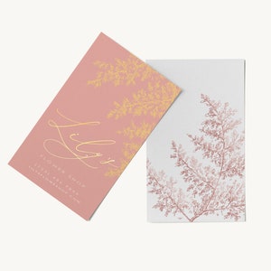 May include: Two business cards with a floral design. The top card is pink with gold lettering that says "Lily's Flower Shop" and a gold floral design. The bottom card is white with a pink floral design.