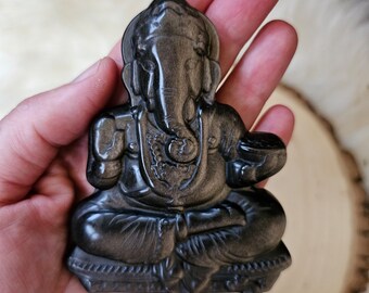Op de afbeelding: Een zwart obsidiaan Ganesha-beeld met gouden accenten. Het beeld zit in een meditatieve houding met zijn slurf omhoog.