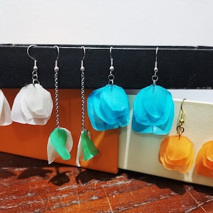 May include: A set of six pairs of earrings featuring layered flower-shaped designs in white, turquoise, green, and orange.