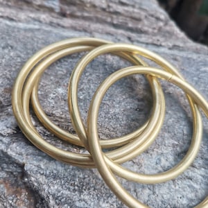 May include: Four gold-colored metal rings stacked on top of each other. The rings are smooth and shiny.