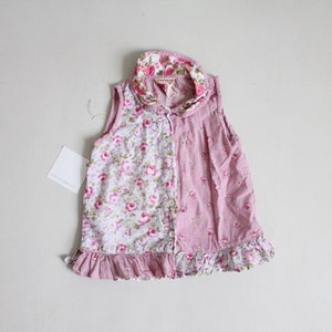 May include: A sleeveless pink and white floral dress with a ruffled hem. The dress has a collar with a floral print.