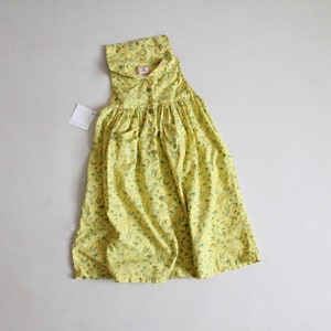 May include: A yellow sleeveless dress with a floral print and a button-up front.