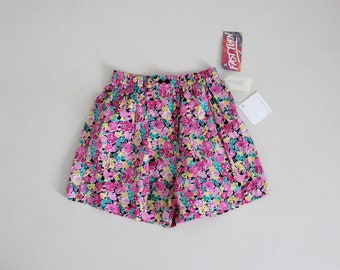May include: Floral print shorts with a black elastic waistband. The shorts have a pink, yellow, and green floral pattern. The tag on the shorts reads "Fast Turn".